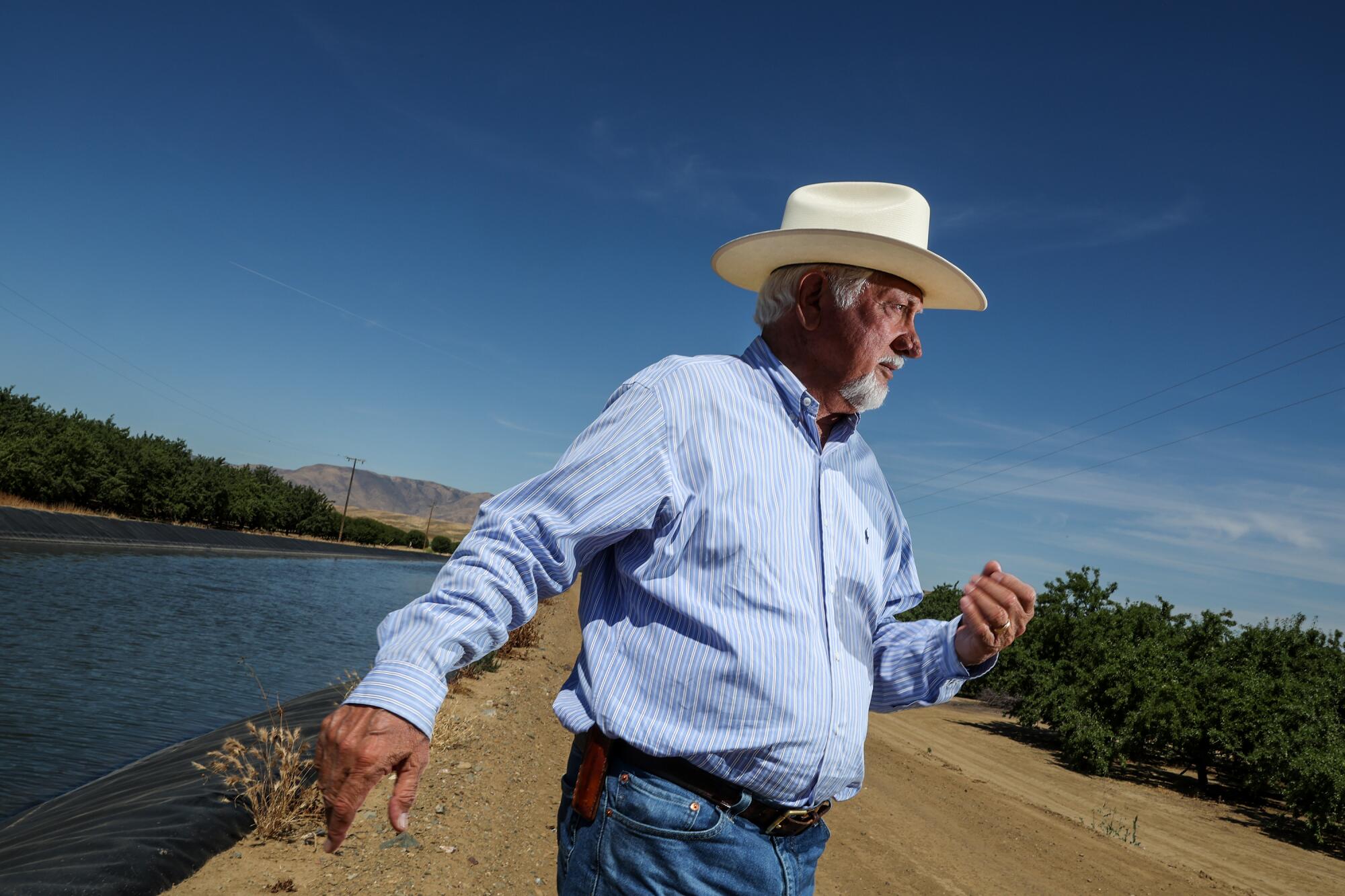 Farmer Joe Del Bosque inspects an orchard beside a canal.