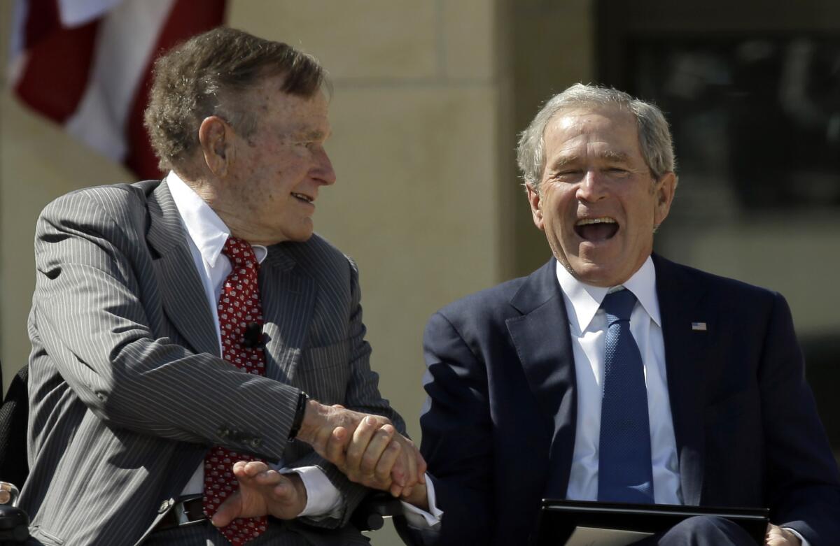 Former President George H.W. Bush shakes hands with his son, former President George W. Bush, during the dedication of the George W. Bush Presidential Center in Dallas. (David J. Phillip / Associated Press)