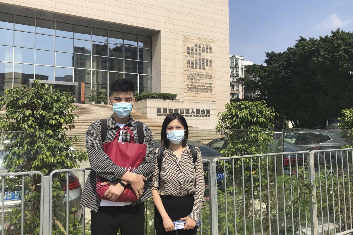 In this photo released by LGBT Rights Advocacy China, a former flight attendant who wants to be known by his surname Chai, left, stands next to his lawyer Zhong Xialu in front of a court in Shenzhen, in southern China's Guangdong Province on Nov. 2, 2020. Chai, a former flight attendant is suing China Southern Airlines for suspending him after his sexual orientation was made public without his consent last year, in a rare legal maneuver that pits him against the country’s largest airline. (LGBT Rights Advocacy China via AP)