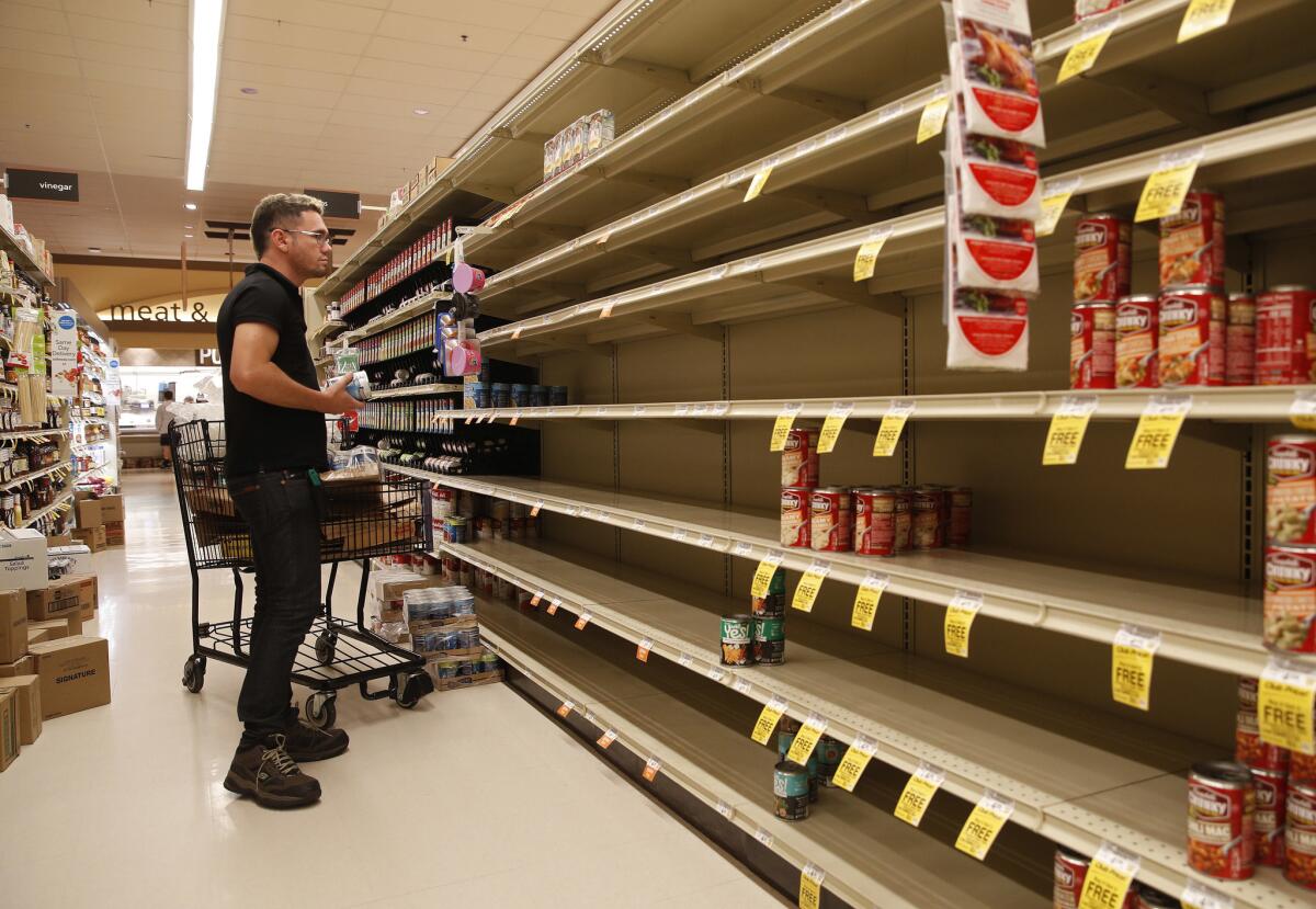 A worker looks at empty shelves for canned goods at a supermarket ahead of Hurricane Lane.