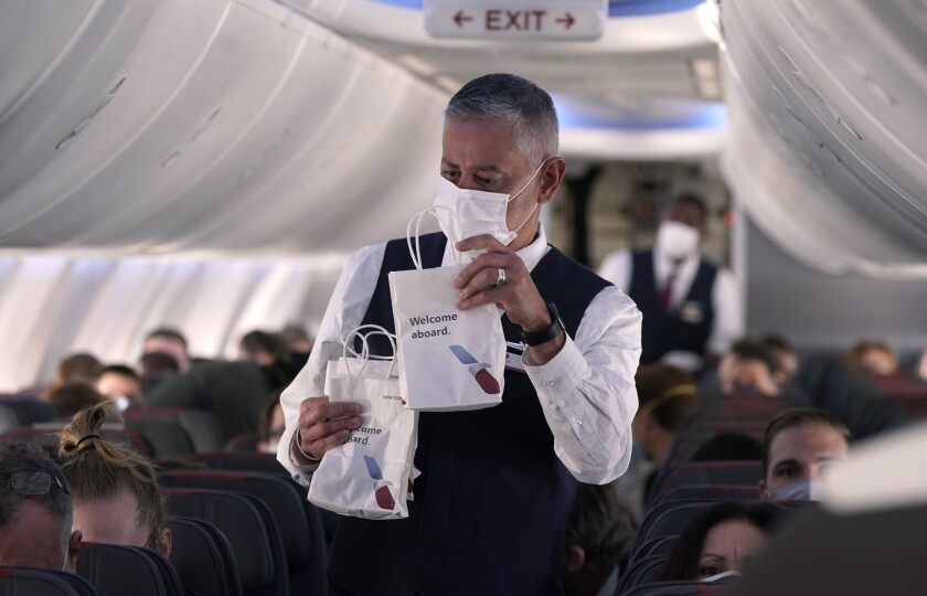 An American Airlines flight attendant hands out snack bags.