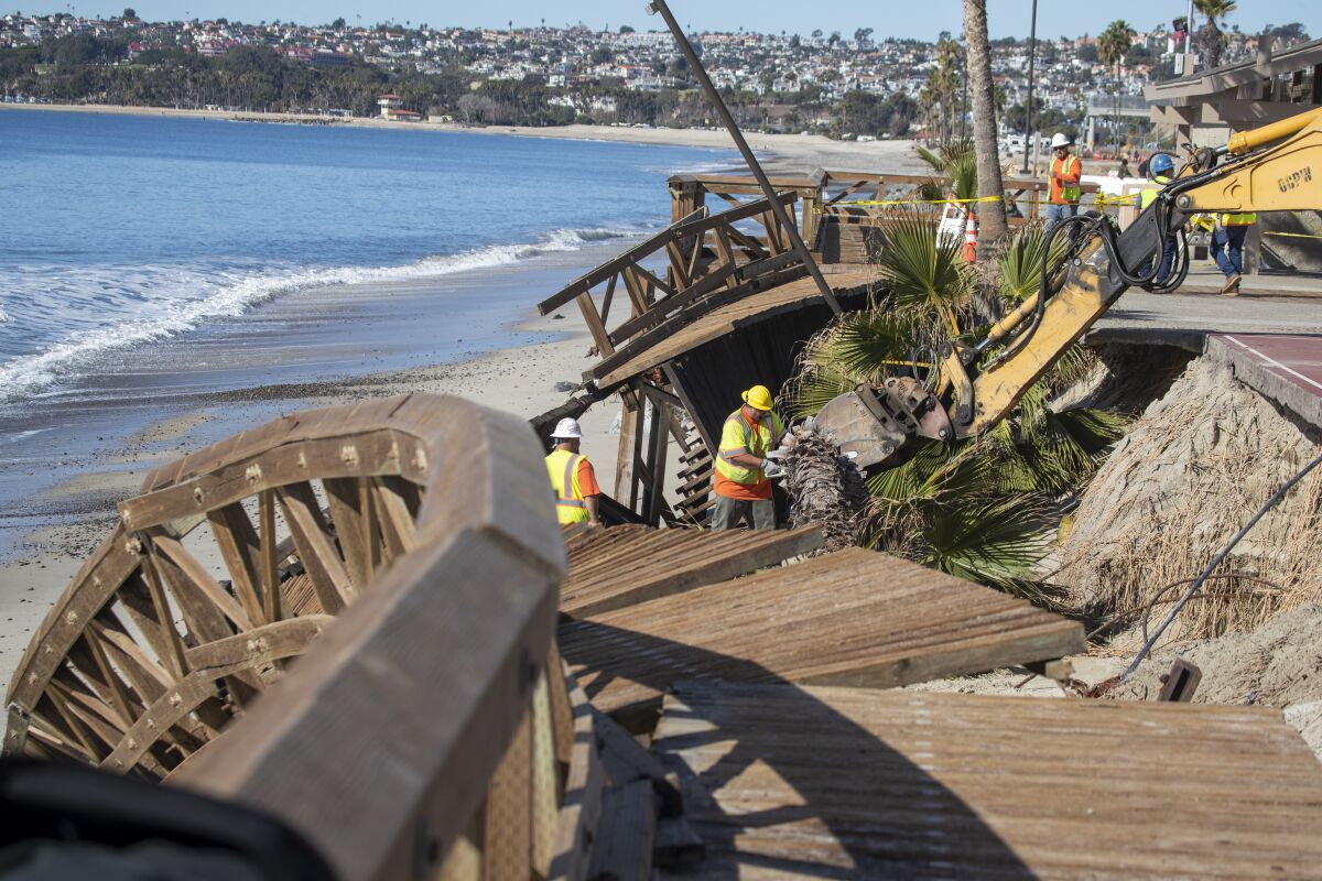 An Orange County Public Works crew uses heavy machinery to remove a boardwalk damaged by a storm at Capistrano Beach in 2018.