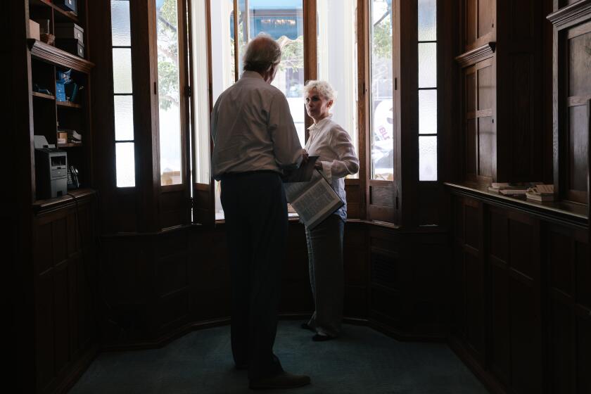 Los Angeles, CA - July 21: Jeffrey Taylor, left, and Deborah Johnson, right, set up their front window with a new reading after service at the Third Church of Christ, Scientist of Los Angeles on Hope Street downtown on Sunday, July 21, 2024 in Los Angeles, CA. (Dania Maxwell / Los Angeles Times)