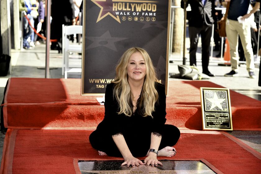 A woman poses with a star on the Hollywood Walk of Fame