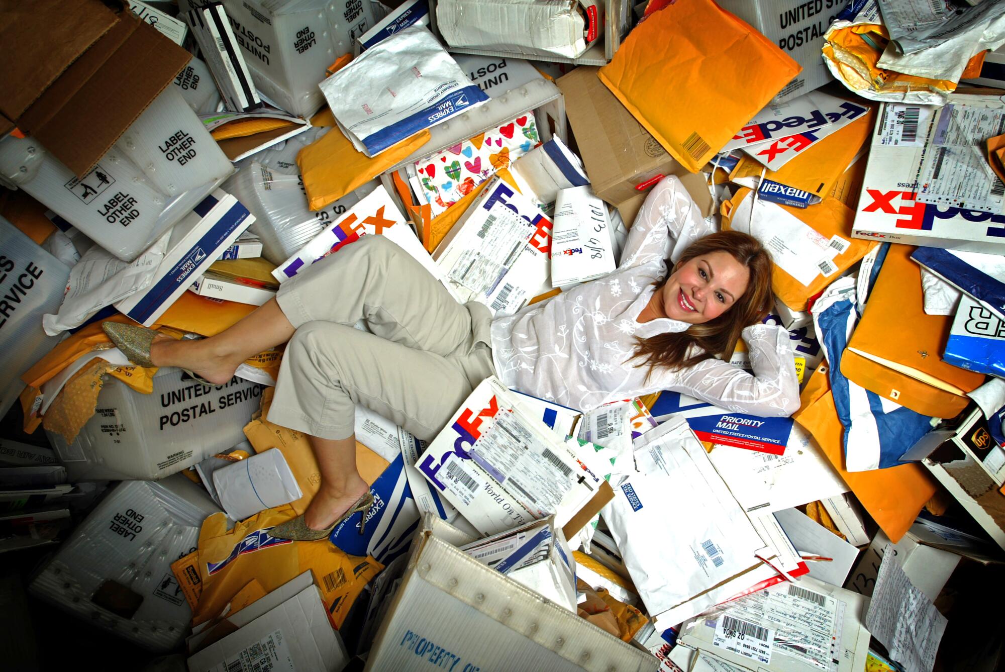 Nely Galán on top of dozens of packages and envelopes strewn on the floor.