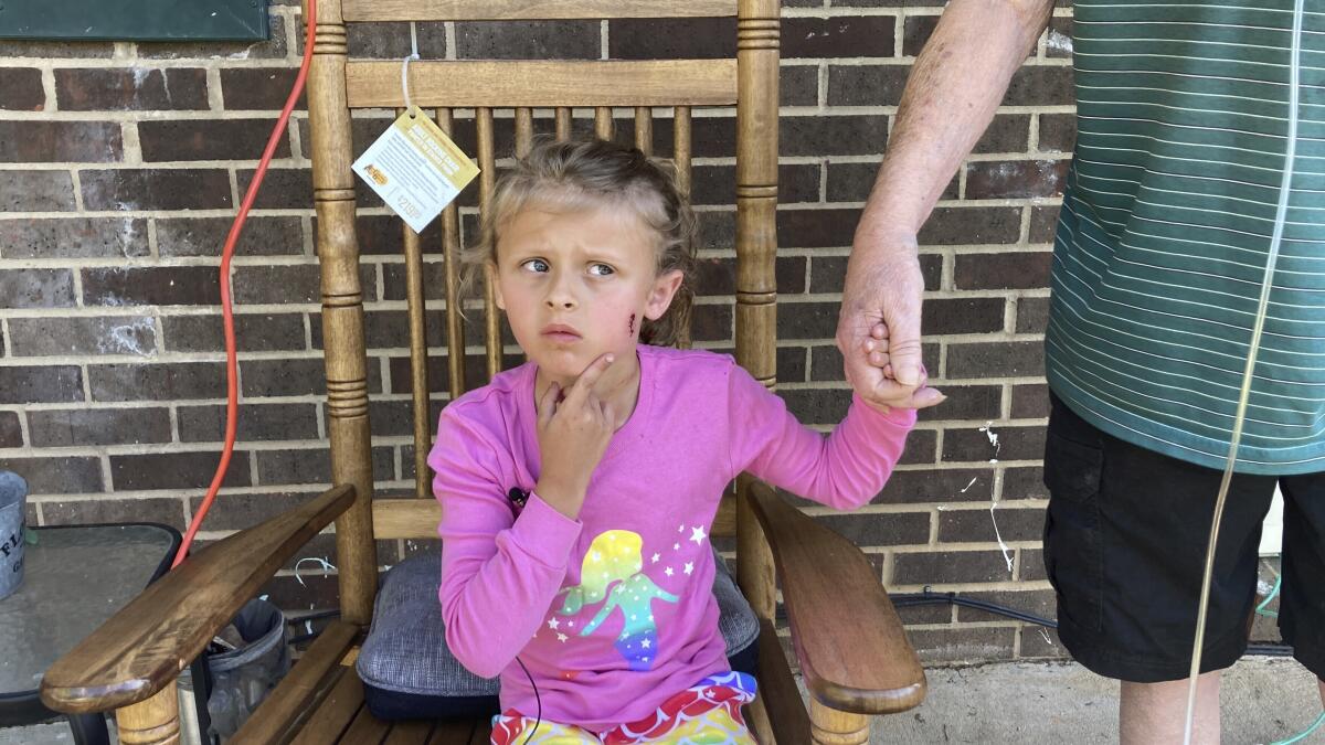 A 6-year-old girl shows reporters a wound on her face.