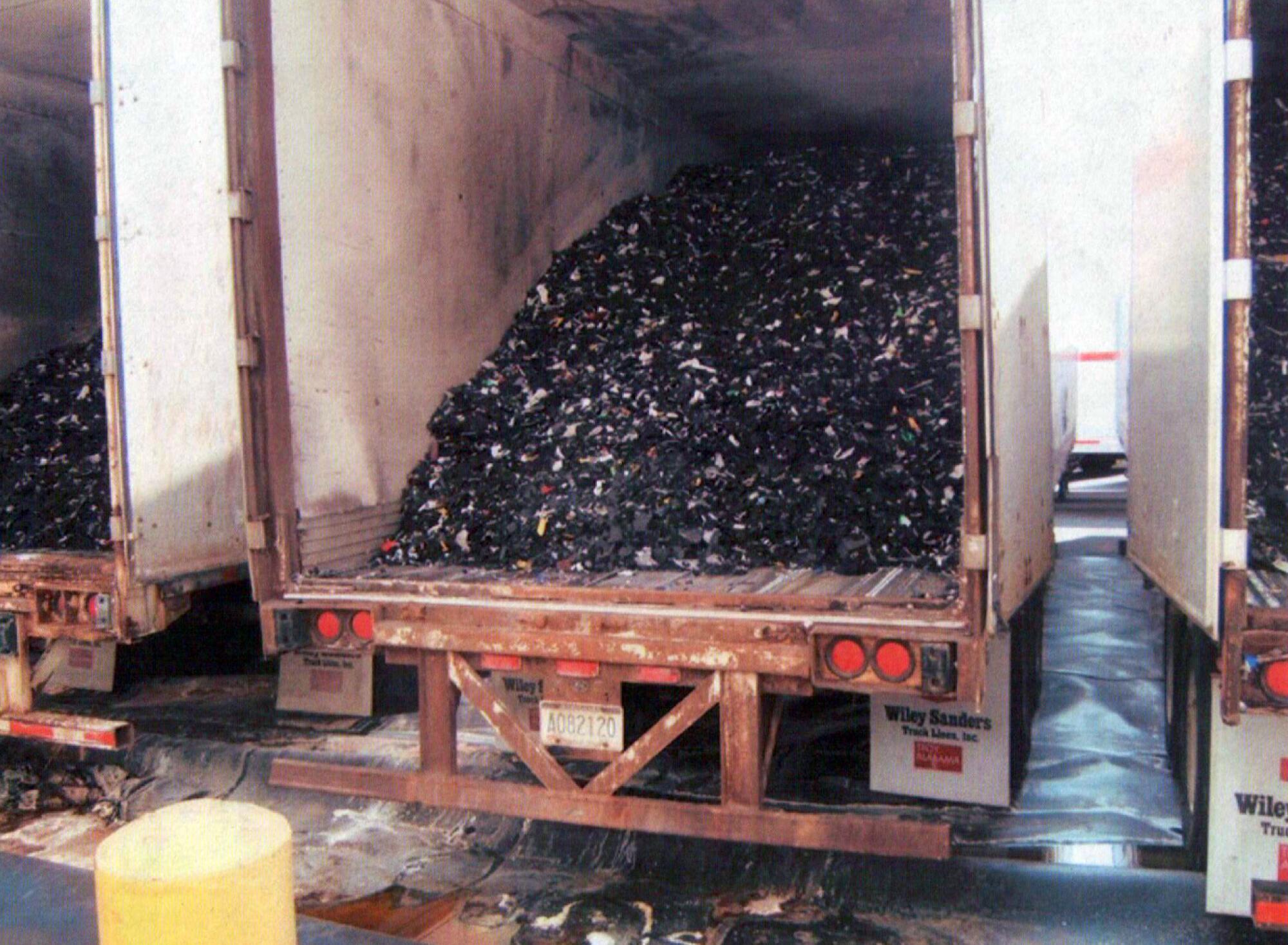 A truck trailer is filled with a dark material.