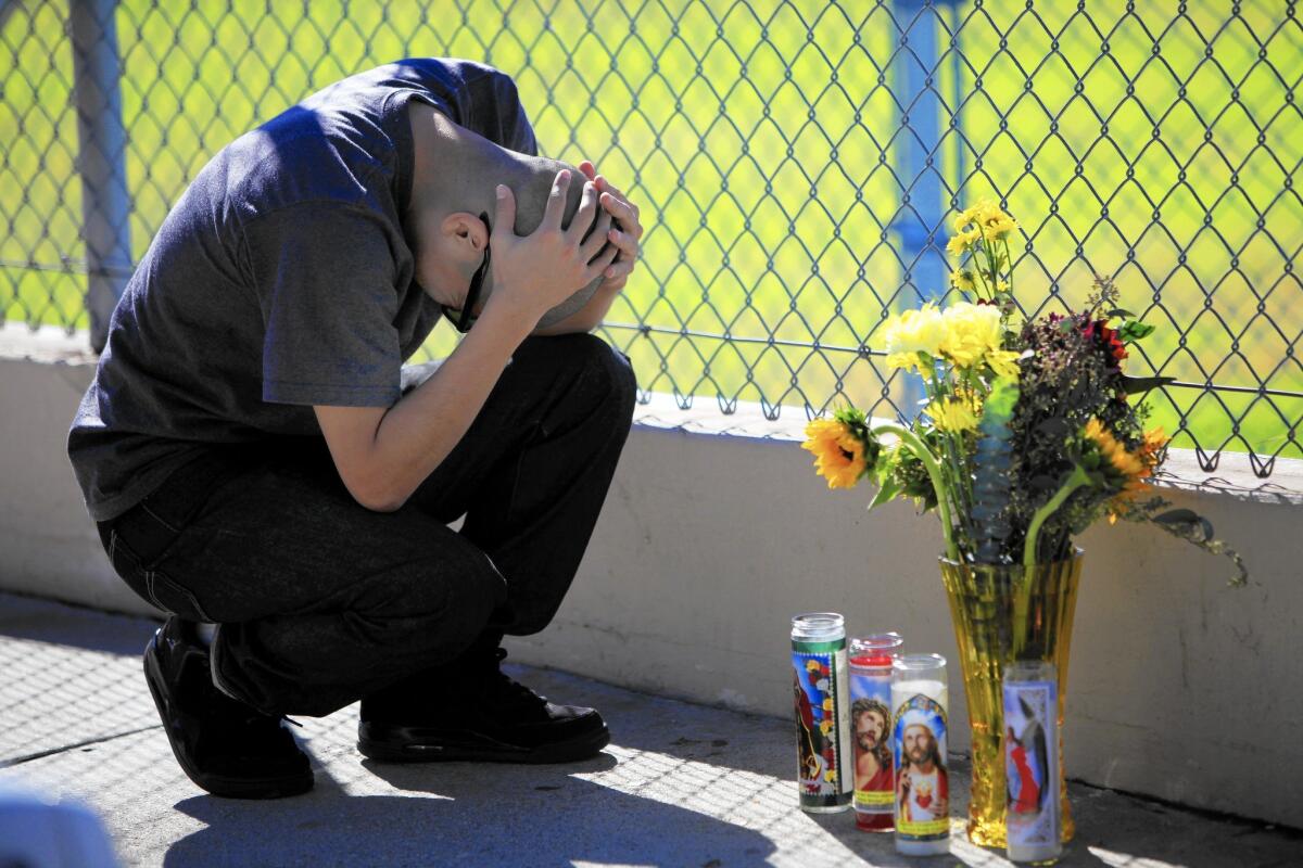 Fernando Mora, 25, of Van Nuys cries next to a makeshift memorial on the sidewalk for his slain friend, Francisco Garcia.