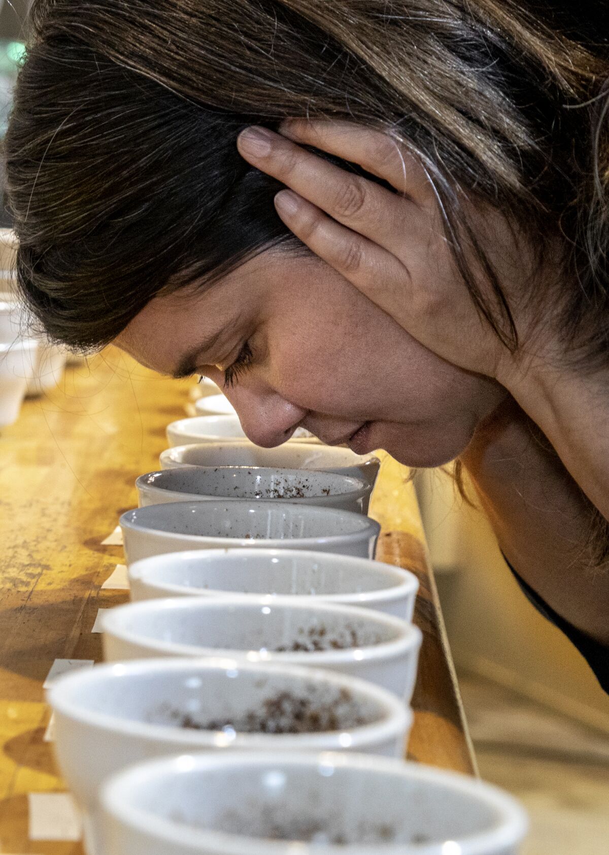 Trish Rothgeb smells the different coffee grounds set out during a tasting session at Wrecking Ball Coffee Roasters