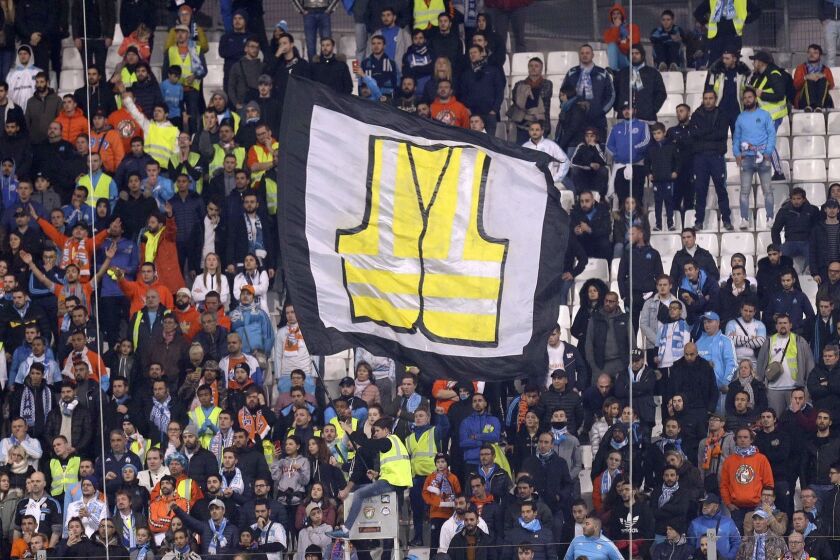 A supporter of Marseille waves a flag representing a giant yellow jacket, in solidarity with the movement of the demonstrators, called yellow jackets, who protest against the rising of the fuel taxes, during the League One soccer match between Marseille and Reims at the Velodrome stadium, in Marseille, southern France, Sunday, Dec. 2, 2018. (AP Photo/Claude Paris)