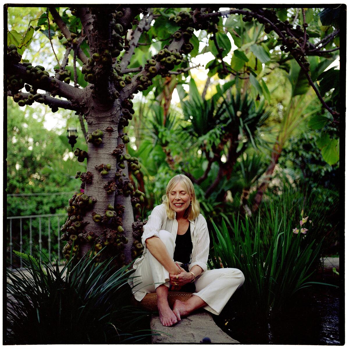Singer Joni Mitchell sits under a fig tree in the courtyard of her Bel Air home. 