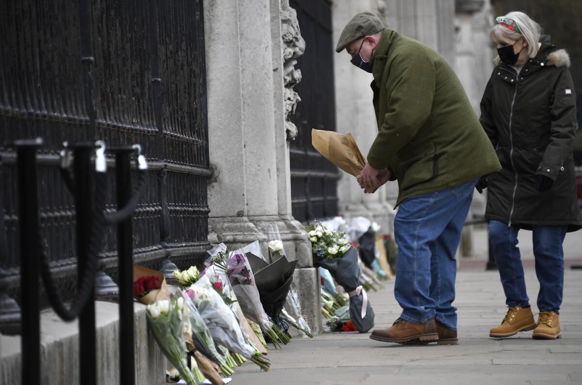 Un hombre deja un ramo de flores en la puerta del Palacio de Buckingham, en Londres, el 10 de abril de 2021