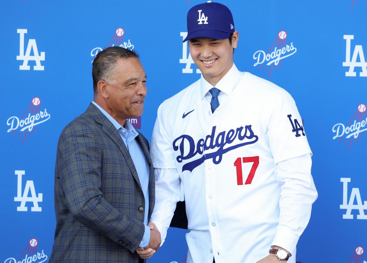 Dodgers manager Dave Roberts, left, shakes hands with Shohei Ohtani on Dec. 14, 2023.