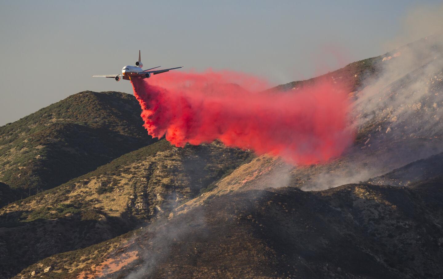 A DC-10 drops fire retardant on the hillsides in Highland, Calif.