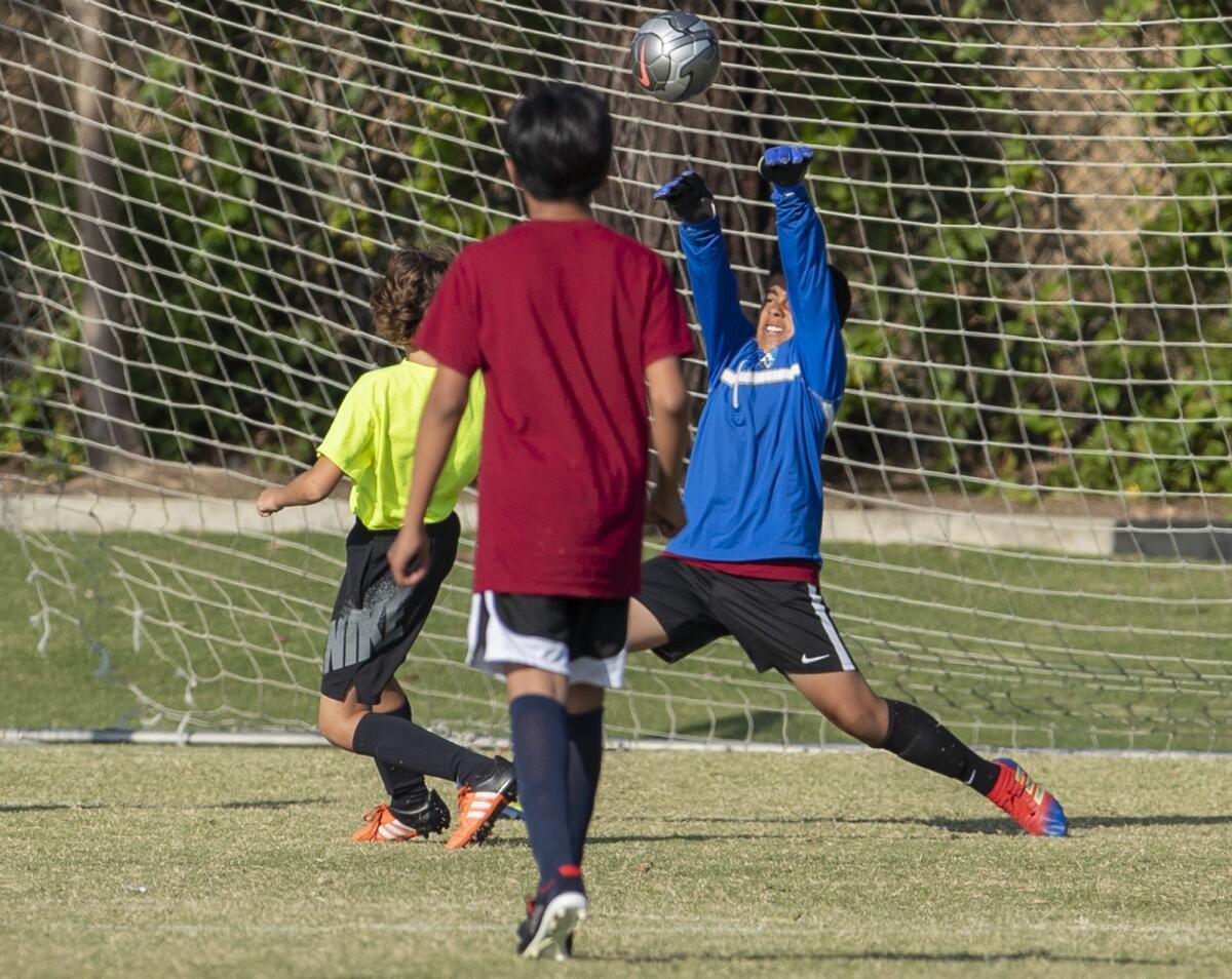 Pomona Elementary goalkeeper Joel Perez blocks a shot by Newport Coast's Grant Davidson in a boys' fifth- and sixth-grade Silver Division pool-play match at the Daily Pilot Cup on Thursday.