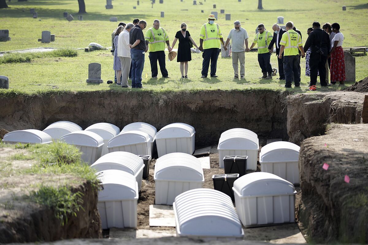 FILE - In this July 30, 2021 photo, a group prays during a small ceremony as remains from a mass grave are reinterred at Oaklawn Cemetery in Tulsa, Okla. People who believe they are descendants of Tulsa Race Massacre victims can now provide genetic material to help scientists try to identify remains of possible victims. The committee overseeing the search for mass graves of victims was told Tuesday, June 21, 2022, that enough usable DNA for testing has been found in two of the 14 sets of remains that were removed from Tulsa's Oaklawn Cemetery a year ago. (Mike Simons/Tulsa World via AP, File)