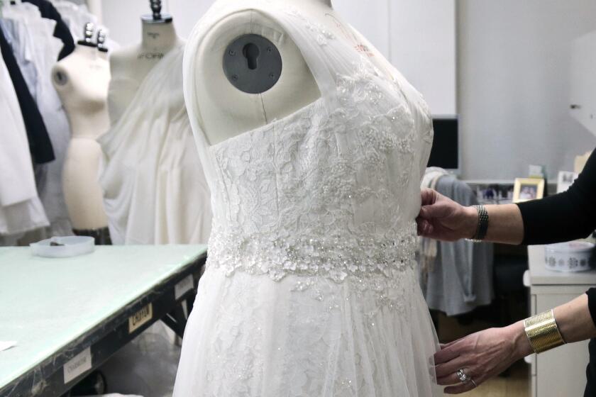 FILE- In this Dec. 17, 2013, file photo, a David's Bridal employee arranges a dress on a plus-size mannequin in New York. David's Bridal is filing for bankruptcy protection but there is no danger for customers who have ordered dresses because operations continuing as normal while the wedding and prom retailer restructures. The bankruptcy filing, the private company said Monday, Nov. 19, 2018, will wipe out more than $400 million in long-term debt. (AP Photo/Bebeto Matthews, File)