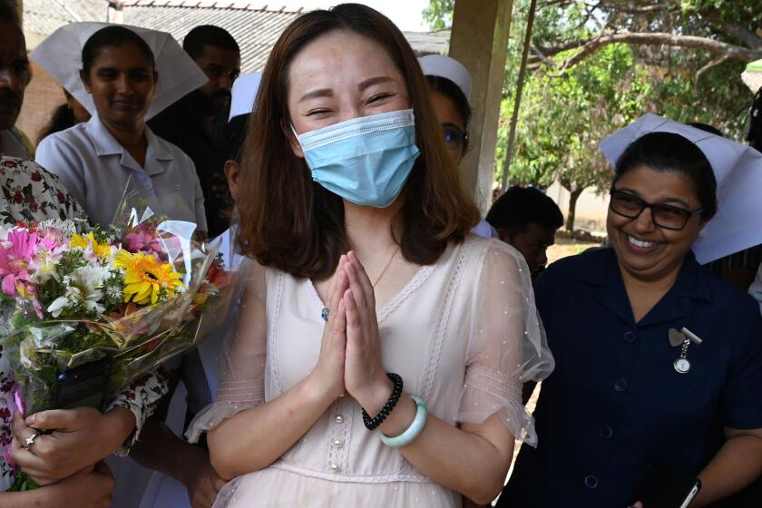 A Chinese tourist (C), who was tested positive for the COVID-19 coronavirus and isolated for treatment, gestures while accompanied by medical staff after she was discharged from the main infectious diseases hospital near Colombo on February 19, 2020, following her recovery. - The 43-year-old woman, the first and only COVID-19 patient in Sri Lanka, was admitted to the hospital on January 25 and tested positive for COVID-19 two days later. (Photo by LAKRUWAN WANNIARACHCHI / AFP) (Photo by LAKRUWAN WANNIARACHCHI/AFP via Getty Images)
