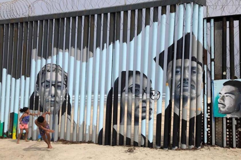 Dos niños juegan frente a un nuevo mural en el lado mexicano del muro fronterizo en Tijuana, México,