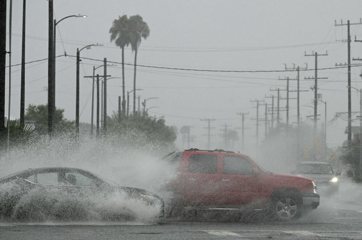Vehicles splash up water during heavy rains from Hurricane Hilary, in south Los Angeles.