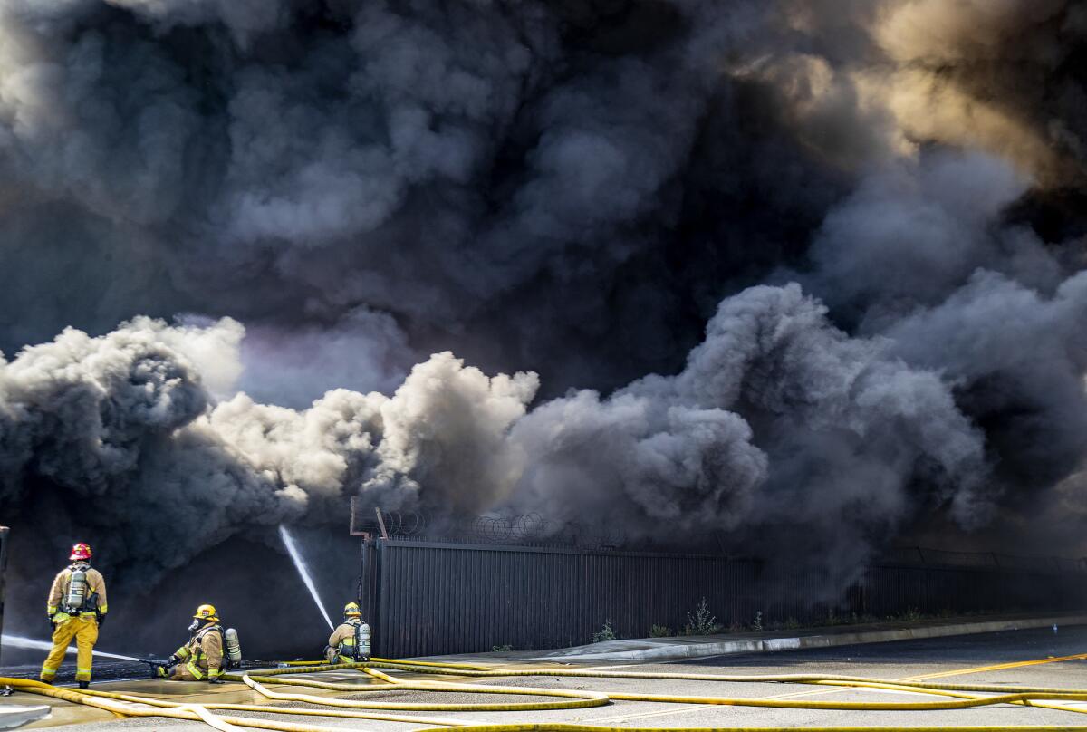 Thick black smoke fills the air Tuesday as Ontario firefighters try to put out a stubborn fire at a recycling plant on East State Street in Ontario, Calif.