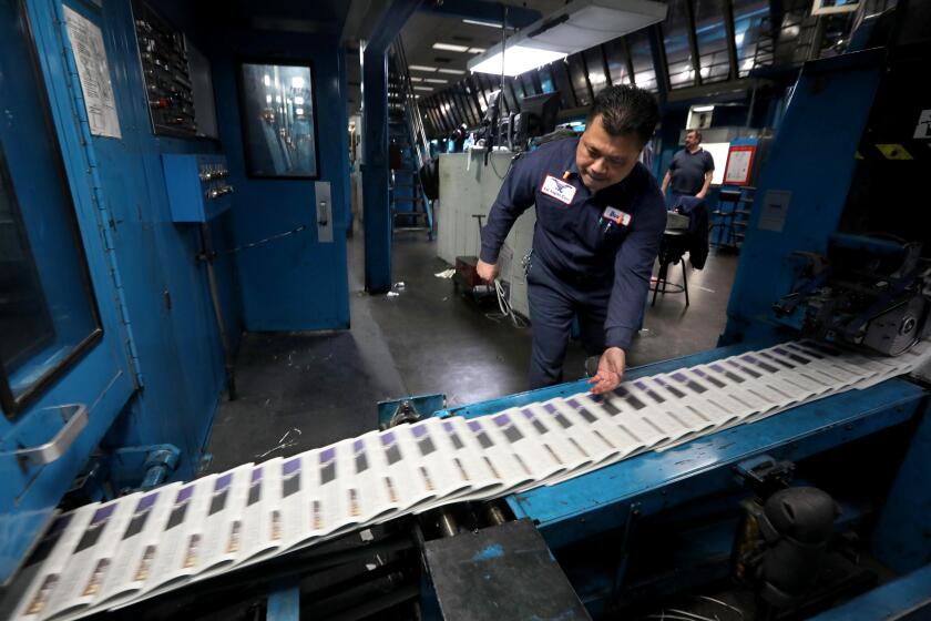 LOS ANGELES, CA - FEBRUARY 23, 2024 - - Ink Specialist David Oma, 50, prepares to pull a paper from the conveyor belt to make sure there is no scumming, that the color is in registration, the margins are set, pagination perfect and the date is accurate at the Los Angeles Times Olympic Printing Plant on February 23, 2024. (Genaro Molina/Los Angeles Times)
