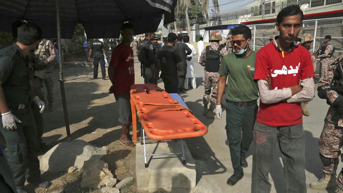 Volunteers wait outside the Chinese Consulate after an attack in Karachi, Pakistan.