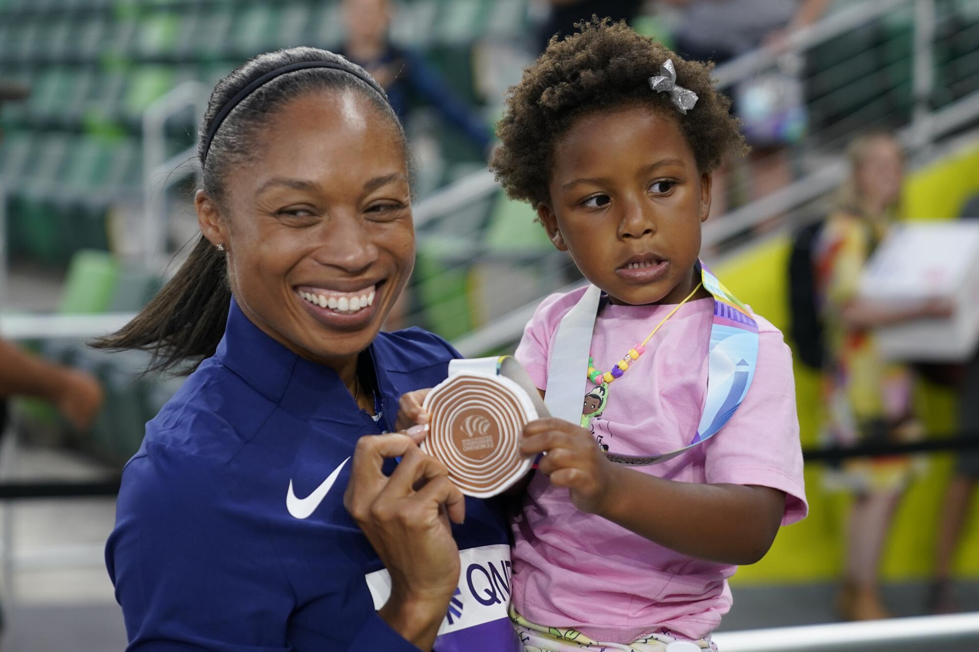 Allyson Felix of the United States gives her daughter Camryn her bronze medal after the 4x400-meter mixed relay.