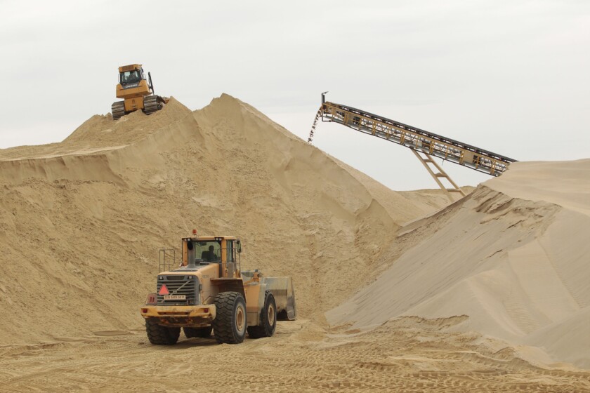 Front-end loaders work in 2012 around a mountain of stockpiled sand waiting to be screened for quality at a mine in Wisconsin.
