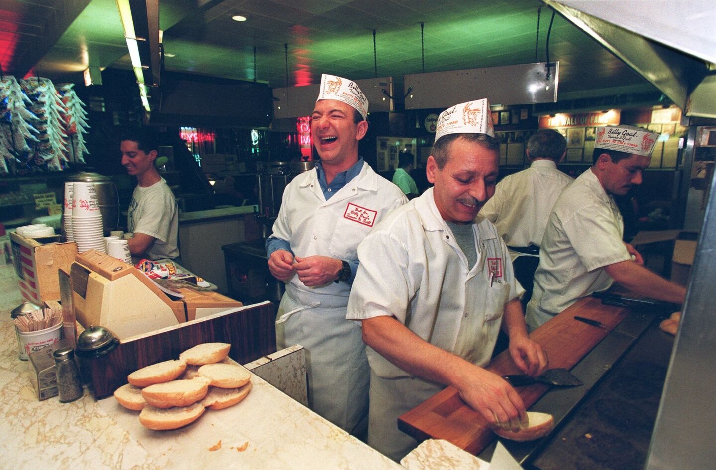Jeff Bezos, founder and CEO of Amazon.com, left, jokes with customers while at the The Billy Goat in Chicago in December 2001. At the grill are Billy Goat employees Spiros Sarivicile, front, and Ramon Gobinic.
