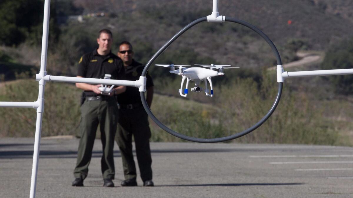 Sheriff's detectives David Chandroo, right, and Justin Crews, left, flew a drone through an obstacle course during training in Ramona in January.