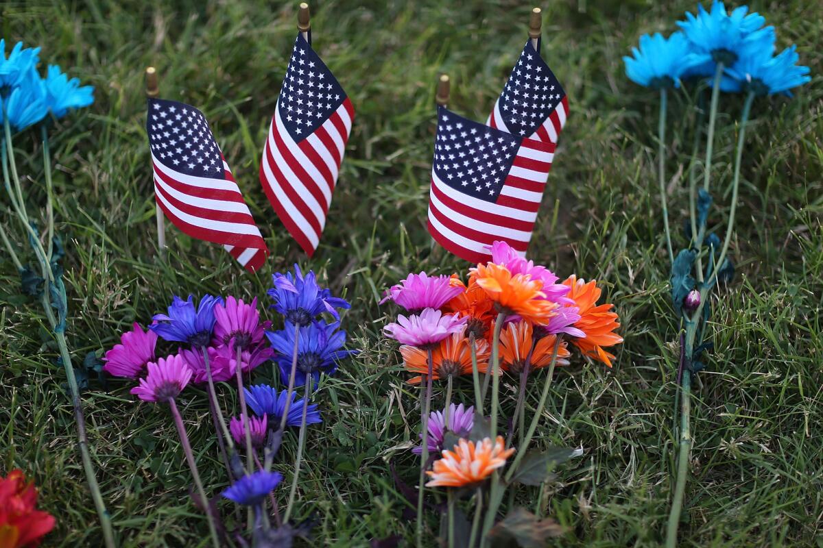 Flowers and U.S. flags adorn a memorial set up in front of the Armed Forces Career Center/National Guard Recruitment Office in Chattanooga, Tenn.