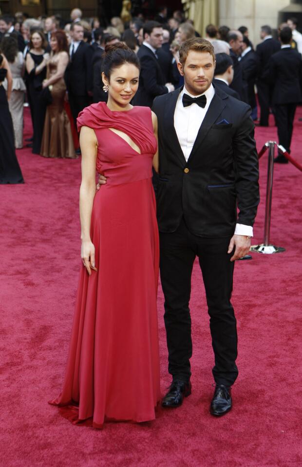 Olga Kurylenko and Kellan Lutz arrive at the 86th Academy Awards in eco-friendly outfits designed by the winners of the Red Carpet Green Dress competition.