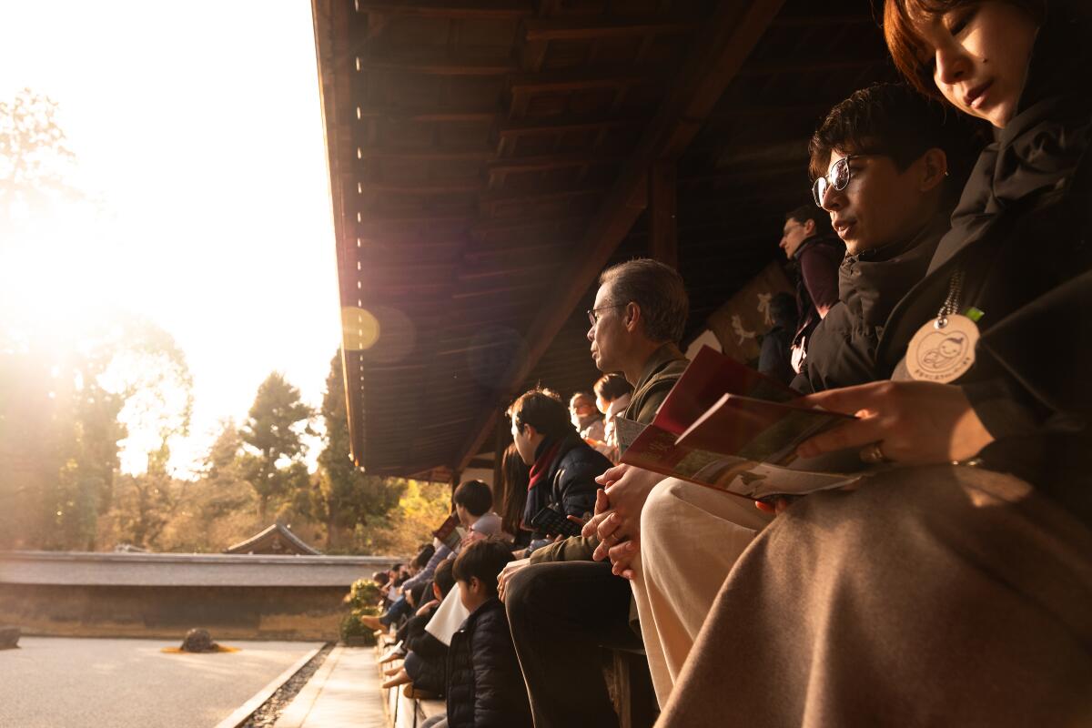 Spectators view a dry garden while seated on a veranda above.