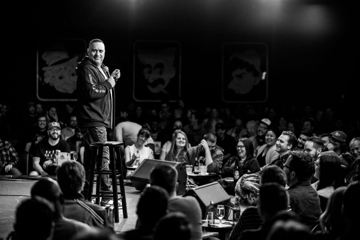 black and white photo of a man doing stand-up in front of a crowd