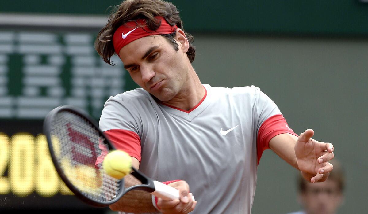 Roger Federer volleys a return against Dmitry Tursunov during a third-round match at the French Open on Friday.