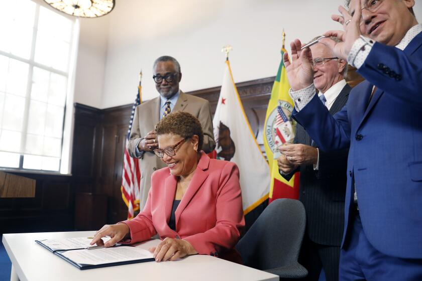 LOS ANGELES-CA-MAY 26, 2023: Surrounded by Councilman Curren Price, Council President Paul Krekorian, and Councilman Bob Blumenfield, from left, Mayor Karen Bass signs the city budget at City Hall in downtown Los Angeles on Friday, May 26, 2023, which includes an unprecedented $1.3 billion investment to address the homelessness crisis, including $250 million for Inside Safe- the new citywide program to bring unhoused Angelenos inside and end street encampments. (Christina House / Los Angeles Times)