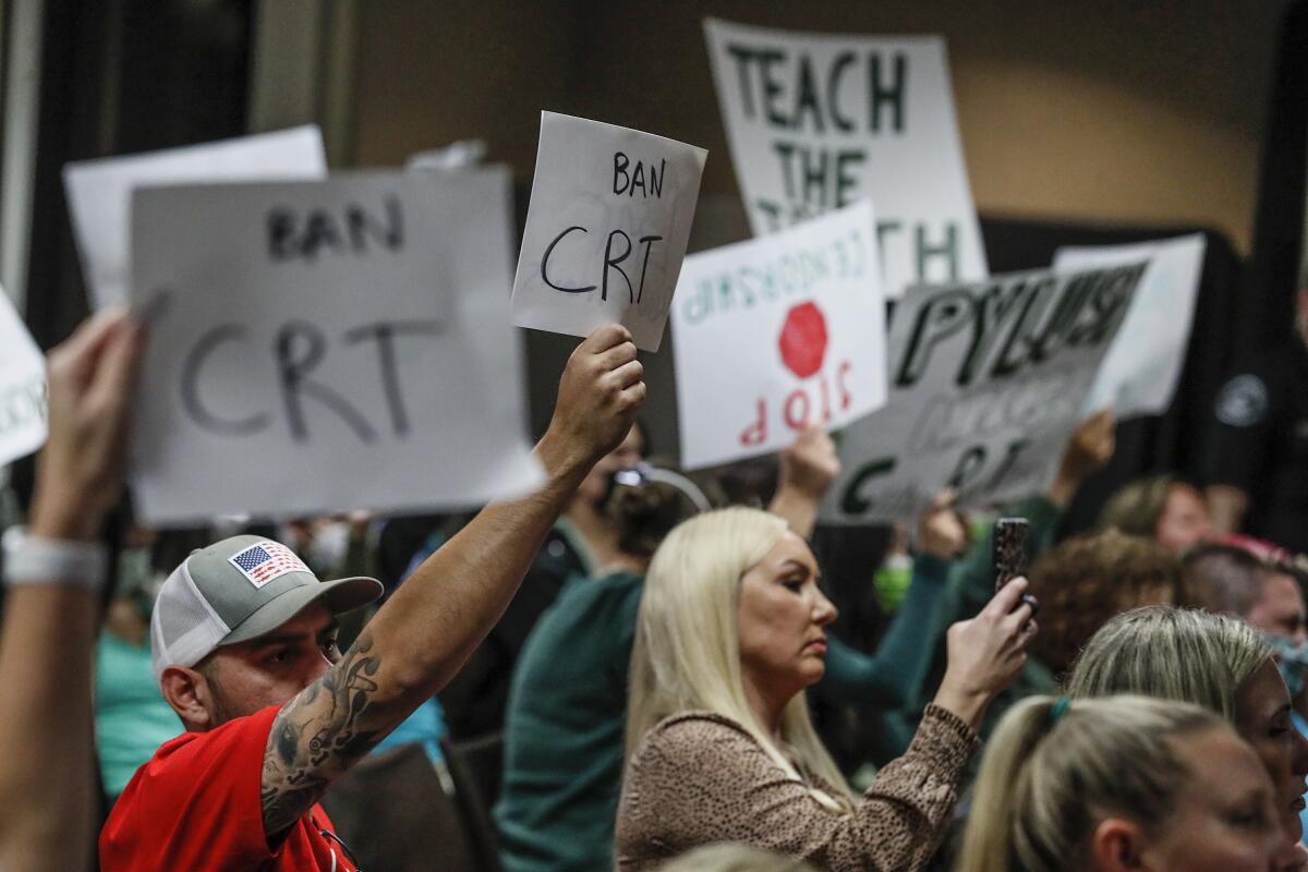 Supporters and opponents of teaching critical race theory hold up signs