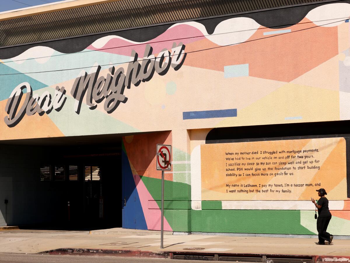 A woman walks below a mural at a building where the nonprofit 1736 Family Crisis Center operates from in Los Angeles.