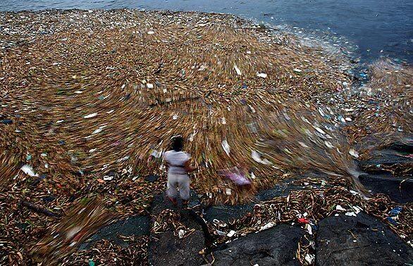A woman scavenges for recyclable cans and plastic from an island of waste in Manila Bay, deposited by the flow of several rivers. Thousands of impoverished Filipinos eke out a living in the low-lying delta areas of Manila Bay in one of the world's most congested and polluted urban areas.