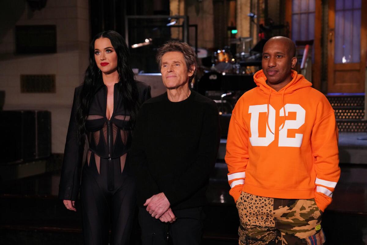 Katy Perry, left, Willem Dafoe and Chris Redd standing on the 'Saturday Night Live' stage