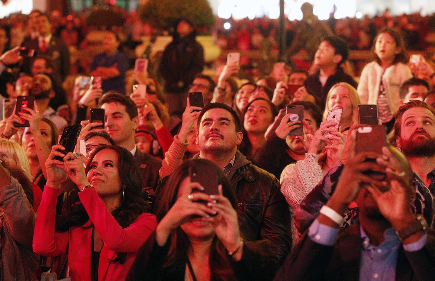 People flooded with red light have their cell phones out for the lighting of the tree at the Americana at Brand for the annual Lighting of the Tree ceremony on Thursday, November 15, 2018. There was a performance before the tree lighting and Santa made an appearance.