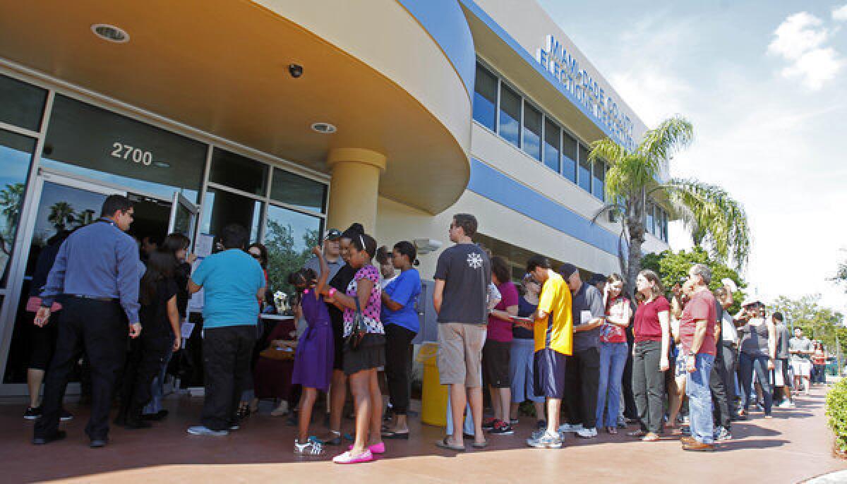 Voters stand in line to pick up absentee ballots in Doral, Fla., on Sunday.