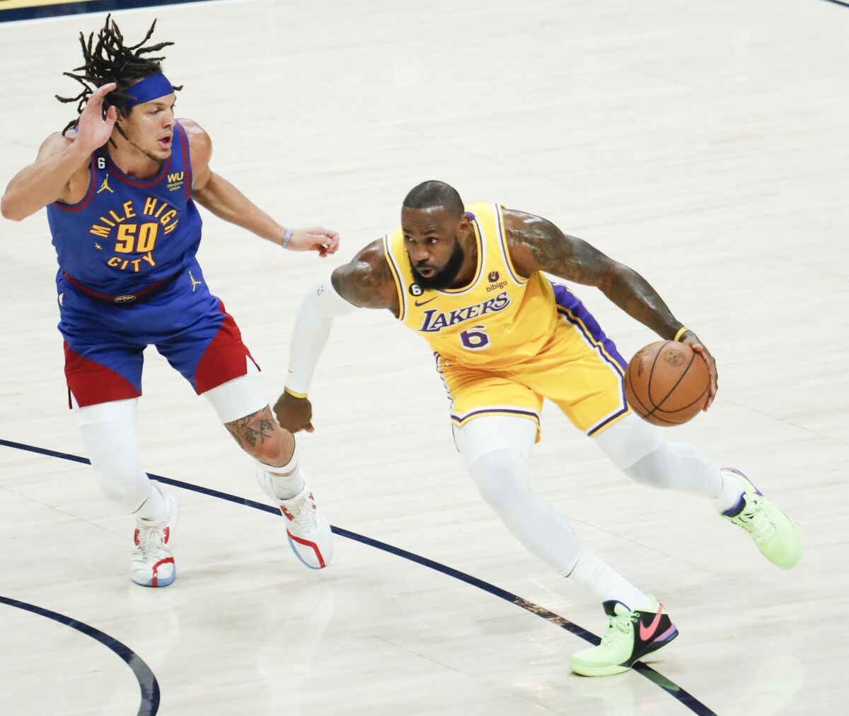 Lakers forward LeBron James, right, handles the ball while defended by Nuggets forward Aaron Gordon.