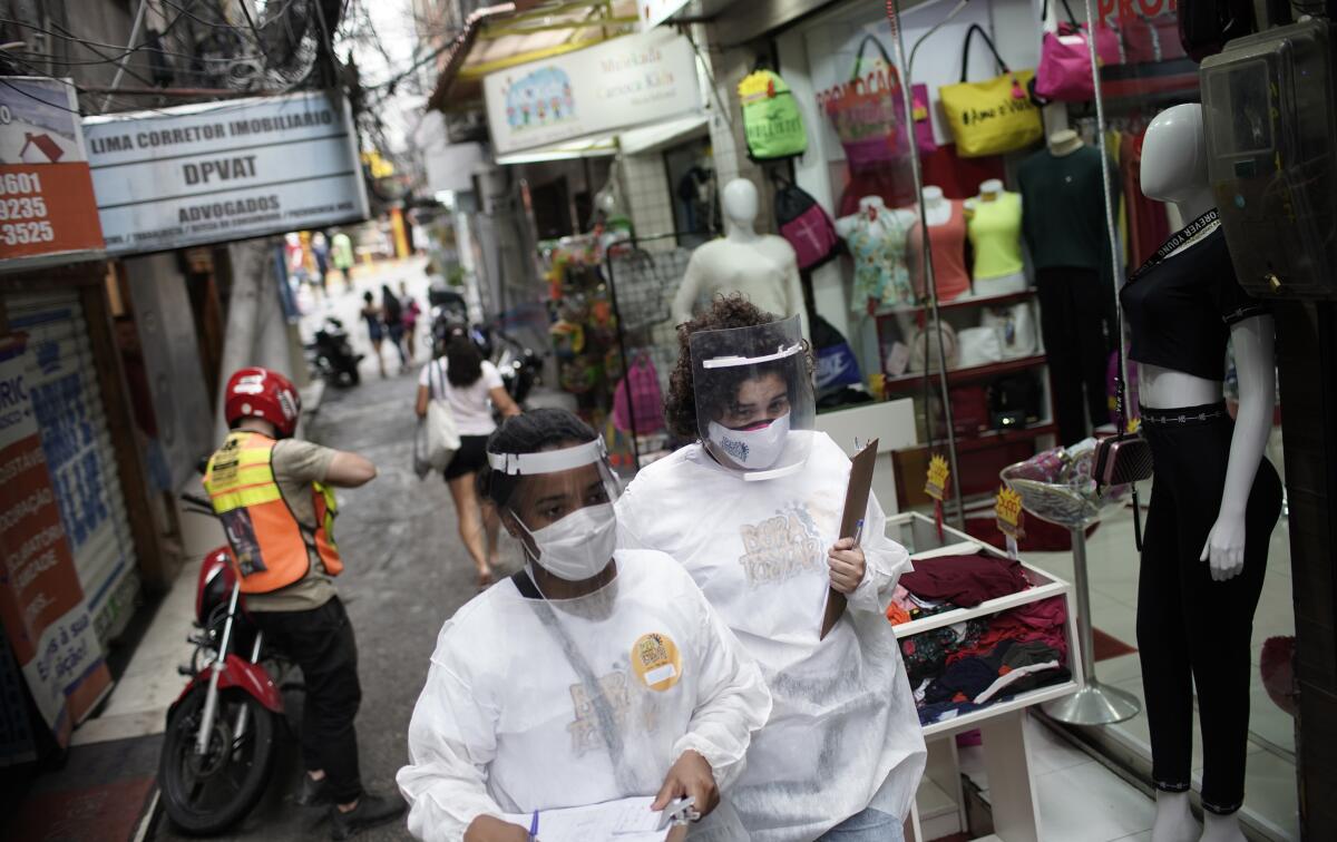 Health workers walk through a slum in Rio de Janeiro to test people for the coronavirus.