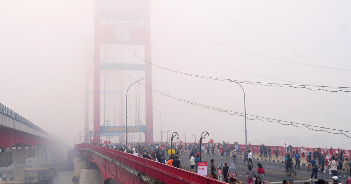 Photo: latimes.com People walk along the Ampera Bridge as haze from wildfires blankets the city of Palembang, in South Sumatra, Indonesia