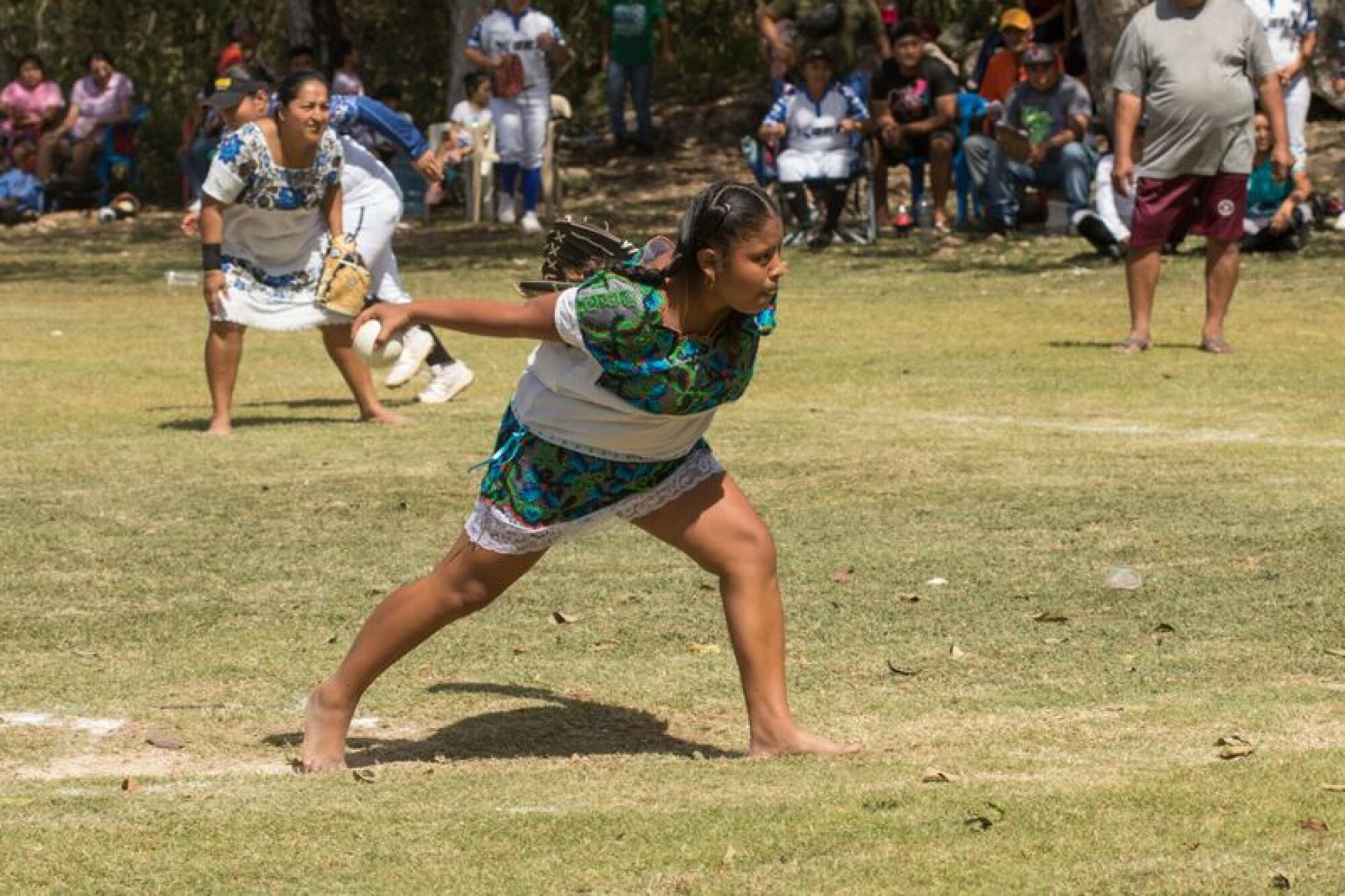 Las Amazonas de Yaxunah, shown wearing indigenous clothing, play a softball game while actor Yalitza Aparicio watches