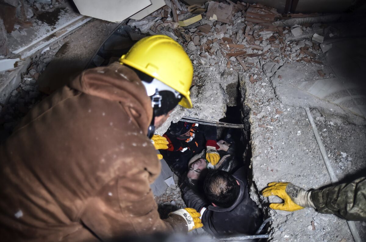 Emergency workers and medics rescue a woman out of the debris of a collapsed building in Elbistan, Kahramanmaras, in southern Turkey, Tuesday, Feb. 7, 2023. Rescuers raced Tuesday to find survivors in the rubble of thousands of buildings brought down by a 7.8 magnitude earthquake and multiple aftershocks that struck eastern Turkey and neighboring Syria. (Ismail Coskun/IHA via AP)