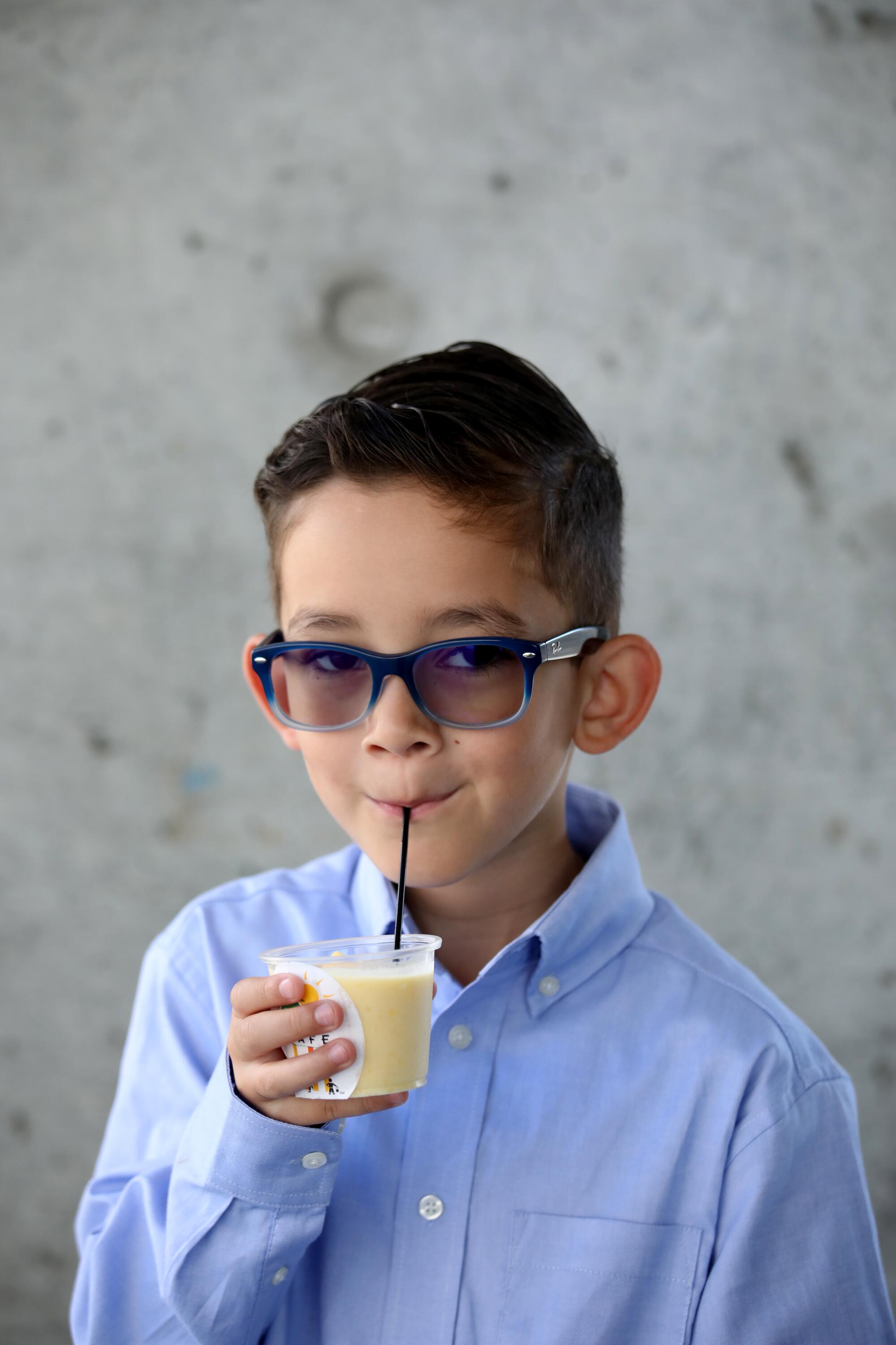 A boy sips a smoothie through a straw.