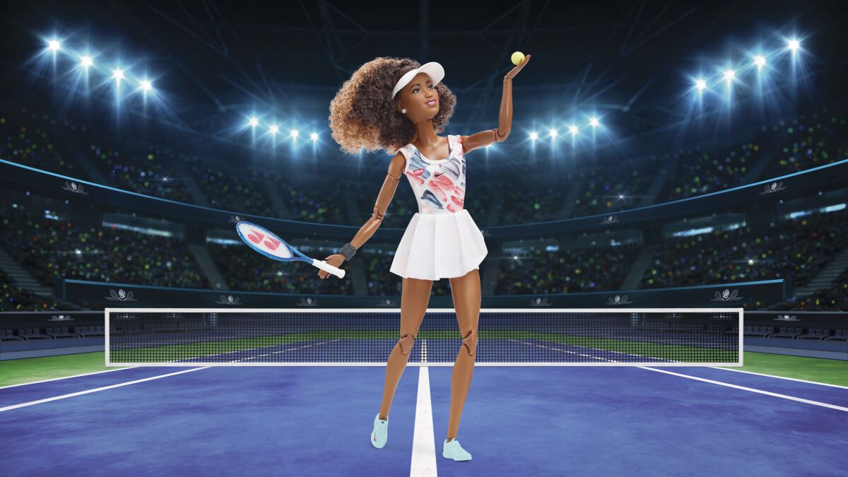 The Naomi Osaka Barbie doll holds a tennis ball while in a pose.
